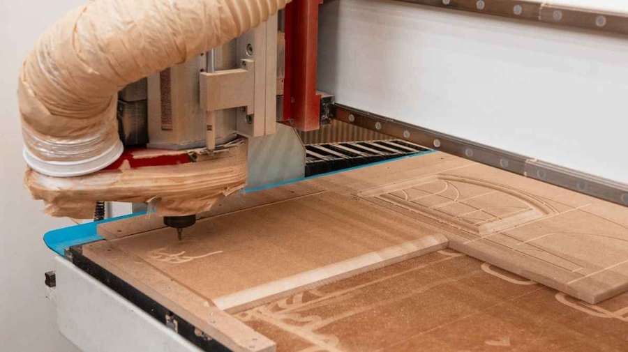 An Image of a CNC routing machine in operation. It actively cuts a detailed pattern into a wooden workpiece