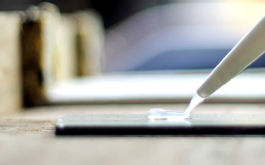 A worker applying adhesive to metal surfaces for bonding