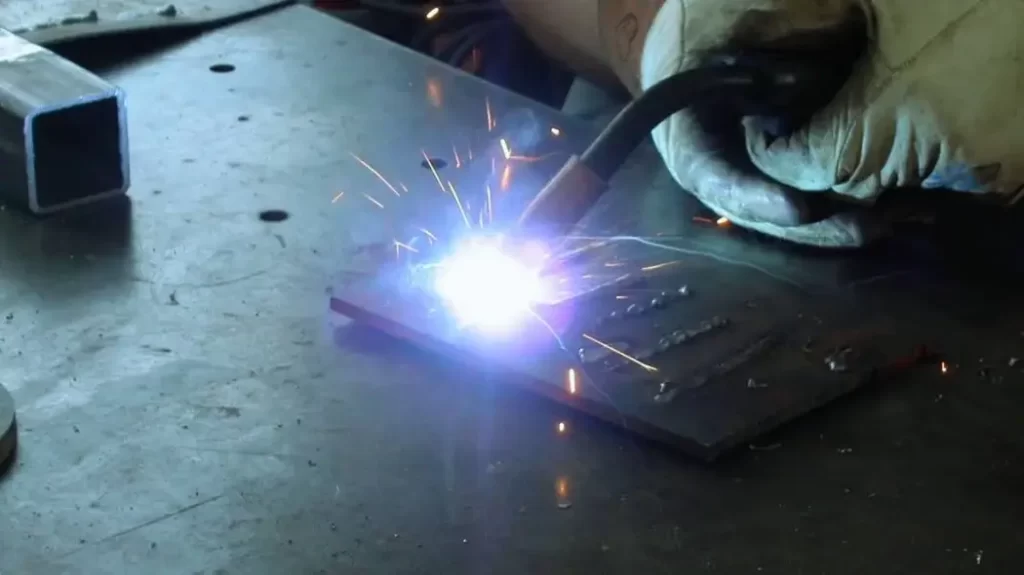 A close-up of a welder using MIG welding to join a part.
