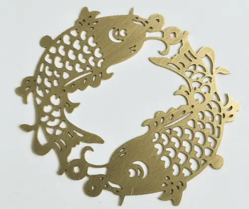 Intricate brass artwork featuring two fish in a circular pattern.