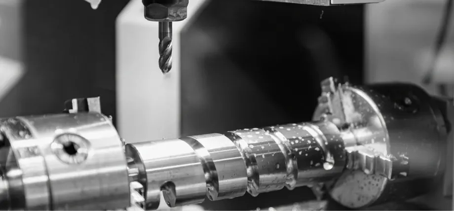 Close up of a large screw under CNC milling with coolant drops and the tool placed at a distance
