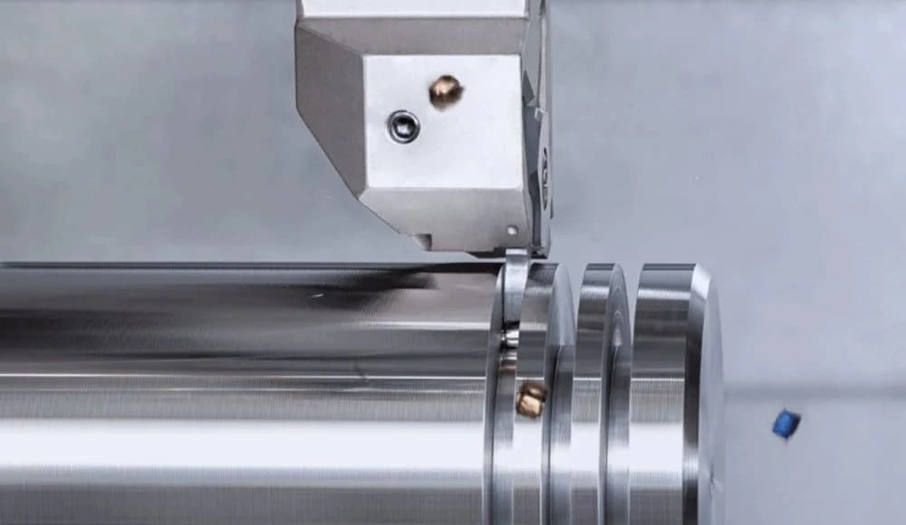 An image showing a cutting tool creating deep grooves on the exterior of a cylindrical shaft. 