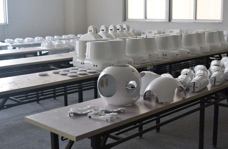 White robotic parts displayed on assembly line tables, demonstrating rapid prototyping and low-volume manufacturing