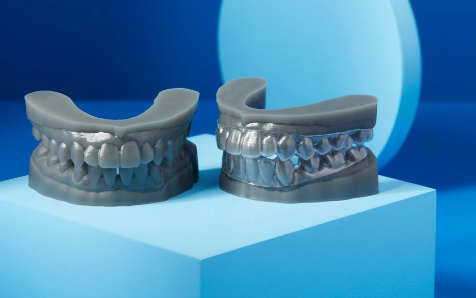 Two grey SLA 3D printed dental components on a blue platform