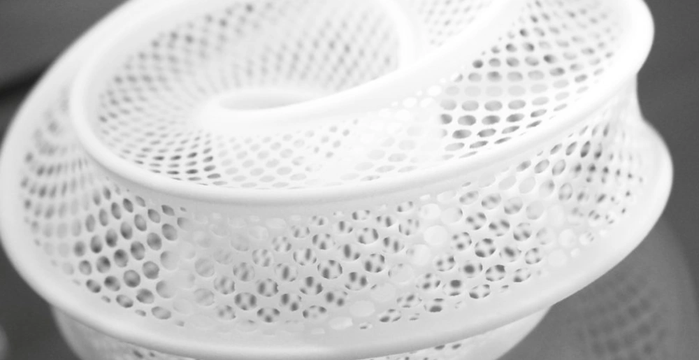 White 3D printed lattice structure with complex perforated geometry showcasing SLS manufacturing 