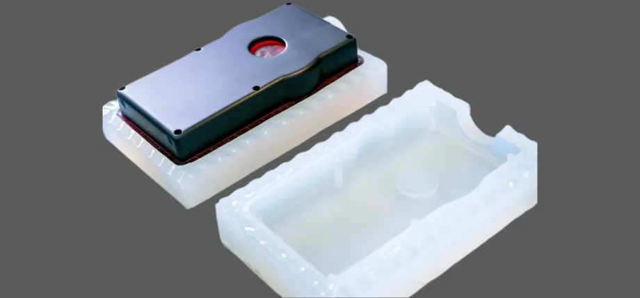 White silicon mold and black vacuum casted part on a grey background