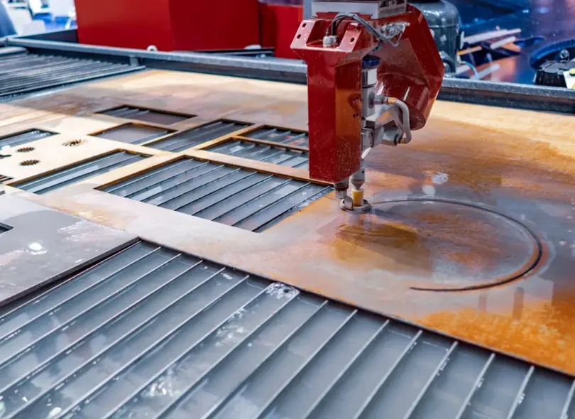 CNC waterjet cutting machine slicing through a metal plate with a high-pressure water stream 